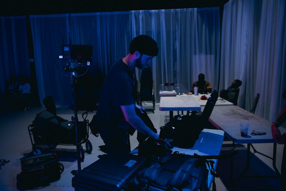 Cinematographer preparing camera equipment on an indoor film set with crew members.